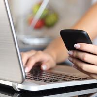 Woman multitasking with phone and laptop