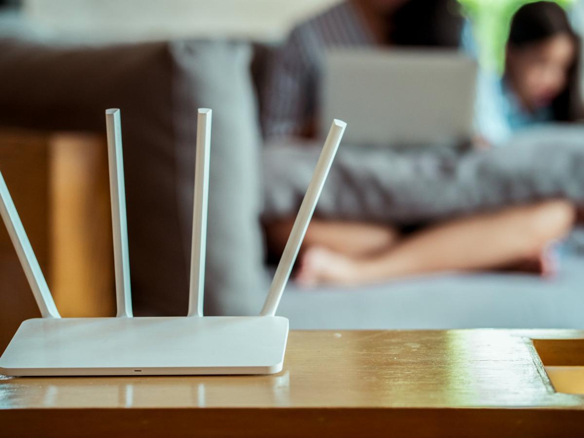 A white Wi-Fi router with four antennas on a wooden table in a living room