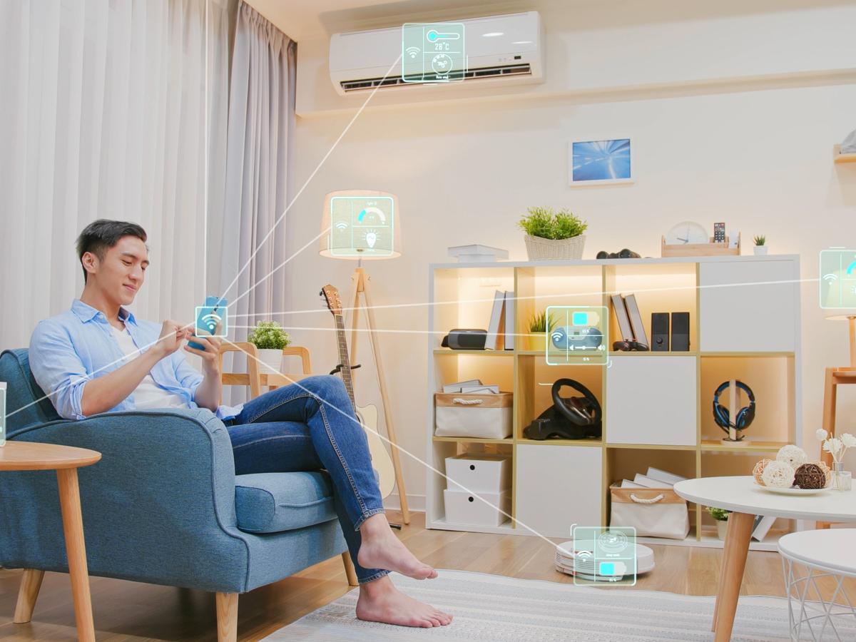 A man on a sofa using his phone to control connected devices around his living room